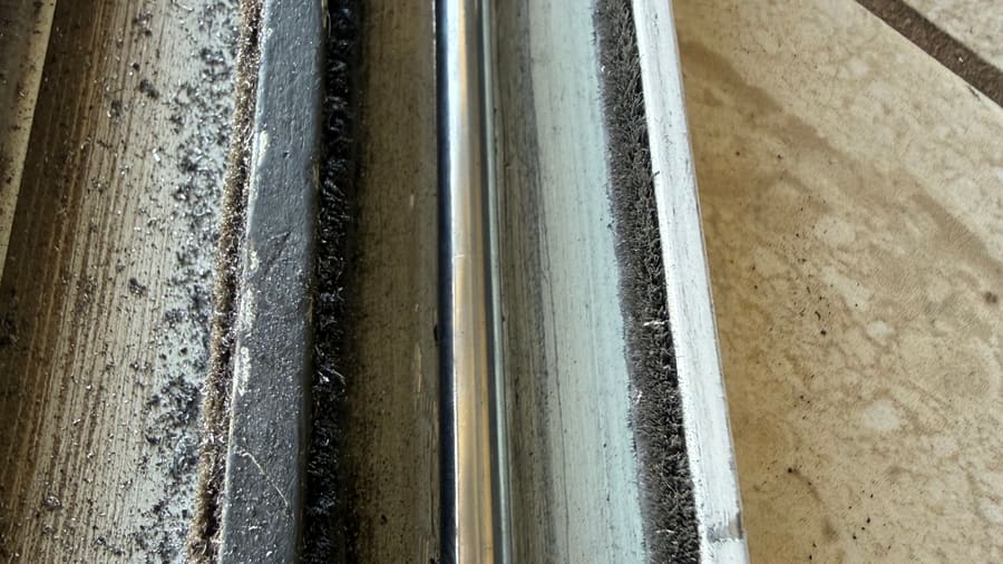 Dirty sliding door track close-up with debris along the rail