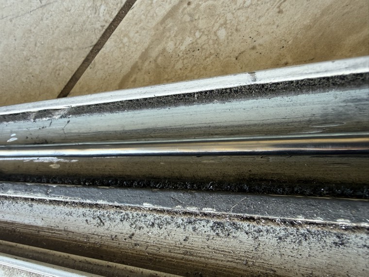 Real lower track channel with uneven buildup along the door path