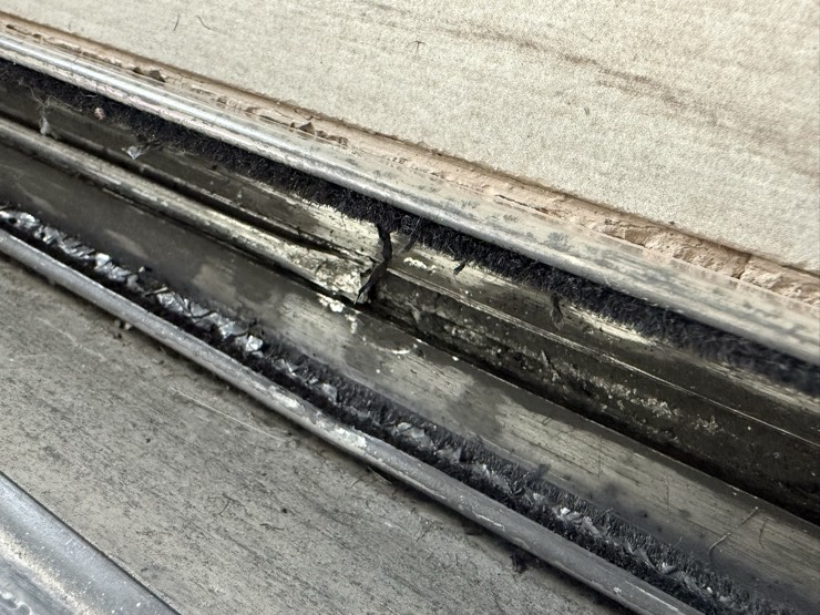 Close-up of a real worn and damaged sliding door lower track